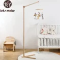 Baby wooden rattle mobile with floor stand bracket hanging over white crib